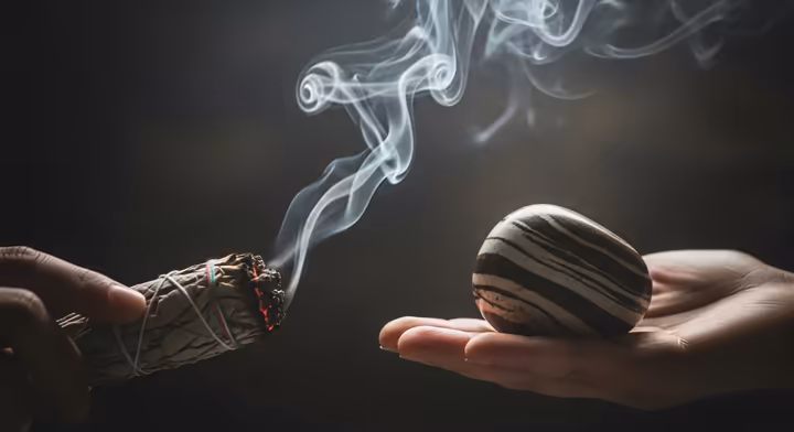 A Zebra Jasper stone being cleansed with the smoke from a smoldering sage stick.
